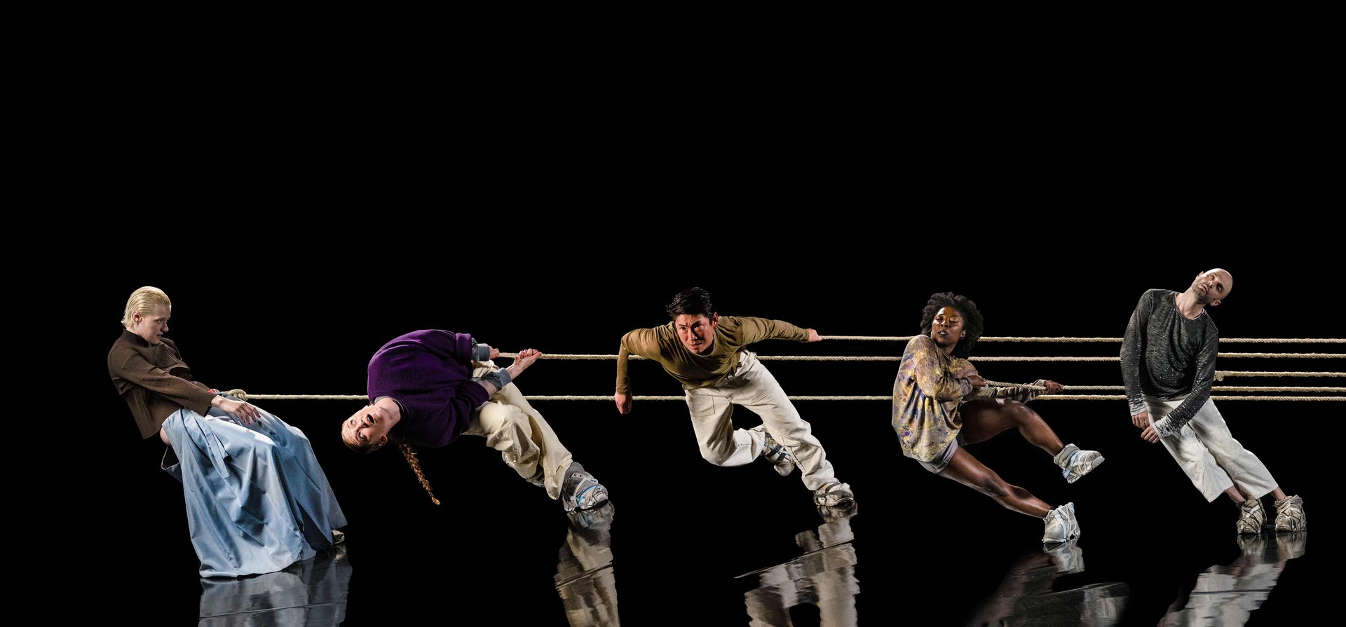 5 People hang from a rope on standing on a mirrored stage