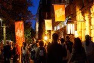 Auf dem Bild sind Menschen vor dem HAU1 nach der letzten Aufführung des Festivals zu sehen. Die Abendbeleuchtung ist eingeschaltet.