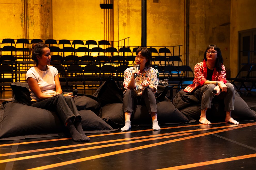 Nguyễn + Transitory wurden zusammen mit Zippora Elders während Beyond the Stage fotografiert. Im Hintergrund sind die Stühle der Tribüne zu sehen und auf dem Boden die Kupferplatten, die während der Performance erklingen.
